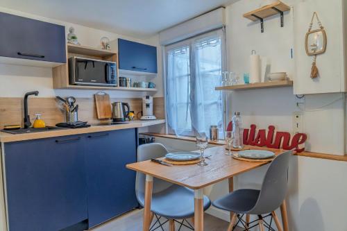 Una cocina con gabinetes azules y una mesa de madera con sillas. en L'Appart'Mans -charmant-studio-centre ville-2 pers, en Le Mans