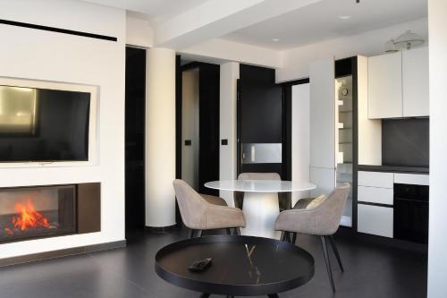 a living room with a table and chairs and a fireplace at White & Black Aegina - Private Garden & Parking in Áyioi Asómatoi