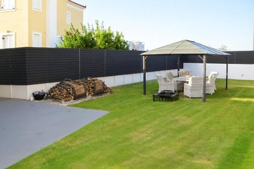 a backyard with a gazebo and a table and chairs at White & Black Aegina - Private Garden & Parking in Áyioi Asómatoi