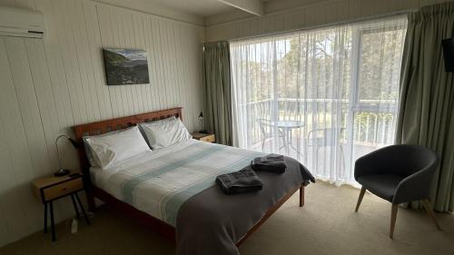 a bedroom with a bed and a chair and a window at One95 Family Beach House in Anglesea