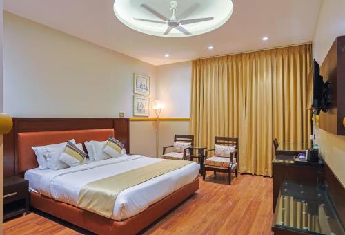 a bedroom with a bed and a ceiling fan at Amber Inn by Orion Hotels in New Delhi
