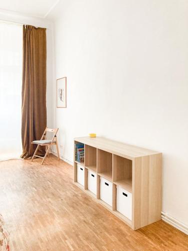 a living room with a book shelf and a chair at Sunny Renovated Ground-Floor Apartment in Neukölln in Berlin