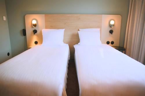 two beds in a room with white sheets at Hôtel Restaurant L'Ours De Mutzig in Mutzig