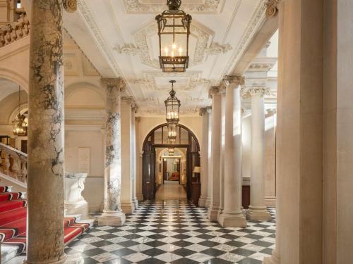 a hallway of a building with columns and a chandelier at Raffles London at The OWO in London