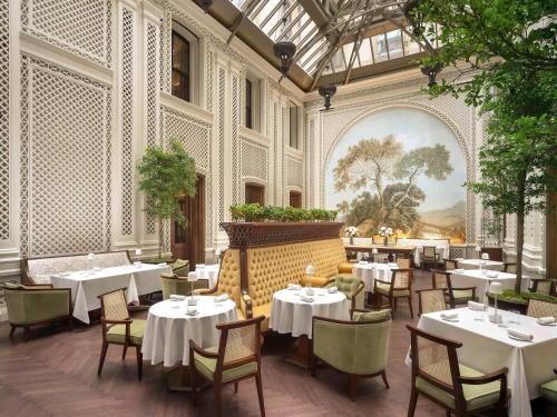 a restaurant with white tables and chairs and a mural at Raffles London at The OWO in London