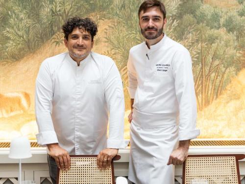 two men in white uniforms standing in front of a table at Raffles London at The OWO in London