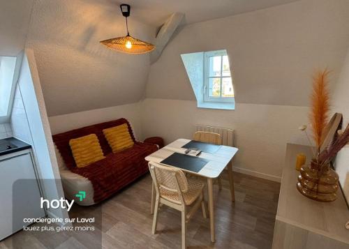 una piccola sala da pranzo con tavolo e divano di L'escale - charmant studio à Laval a Laval