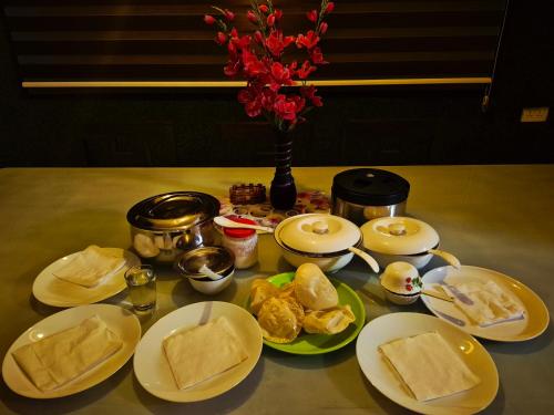 a table with plates of food and a vase with flowers at Skylark Home in Mananthavady