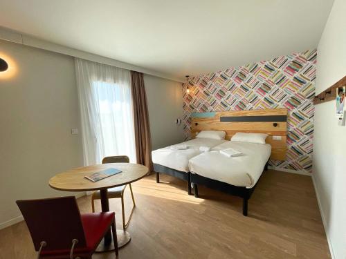 a hotel room with a bed and a table and a table sidx sidx at greet hotel Castets Coeur des Landes in Castets