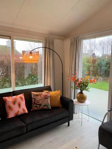 a living room with a black couch and a window at Bungalow 001 in Petten