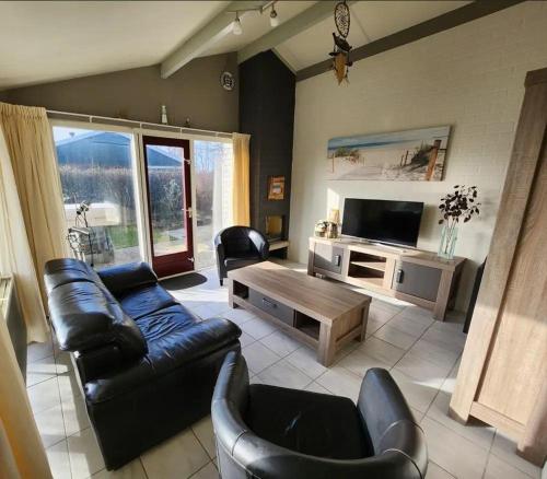 a living room with a couch and a tv at Bungalow 002 in Petten