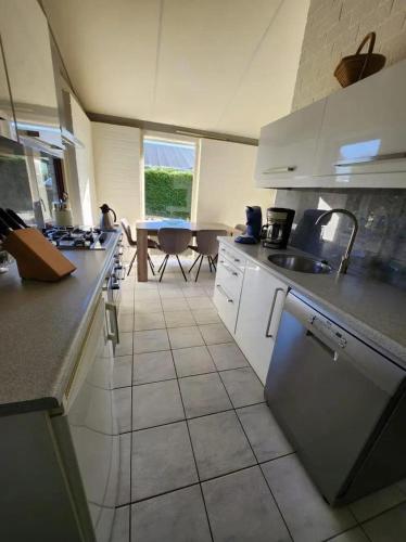 a kitchen with white appliances and a table in the background at Bungalow 002 in Petten