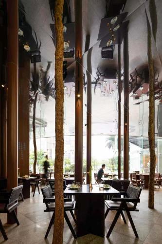 een restaurant met tafels en bomen aan het plafond bij Prime Pazhou Aparthotel - Pazhou Station Line 8 and 11 - Steps away from Canton Exhibition Center in Guangzhou