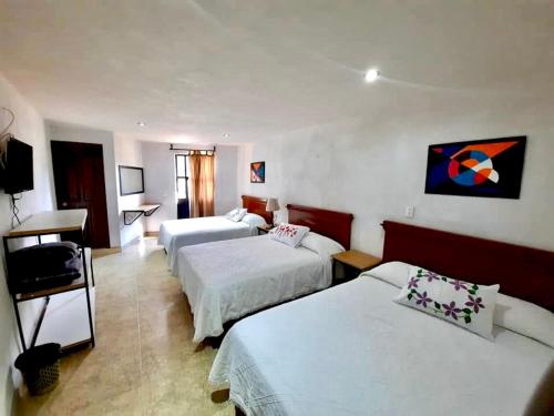 a hotel room with two beds and a desk at Hotel de la Parroquia in Tlalpujahua de Rayón