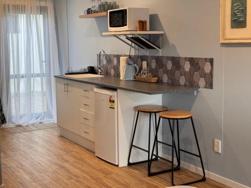 a small kitchen with a counter and two stools at Jamarqui Barn Cottages in Ohaupo