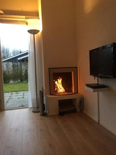 a living room with a fireplace with a tv at Bungalow 027 in Petten