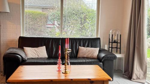 a black leather couch with two red candles on a coffee table at Bungalow 028 in Petten