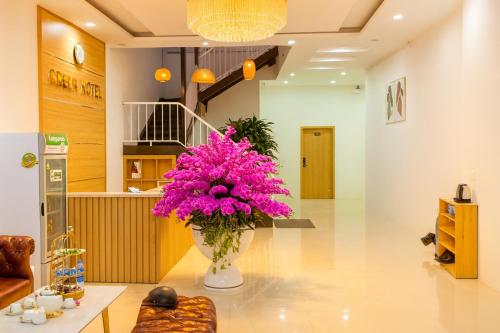 a vase of pink flowers on a table in a room at Green Hotel Cao Bằng in Cao Bằng