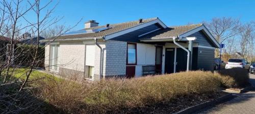 a small white house with a blue roof at Bungalow 038 in Petten