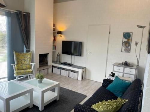 a living room with a couch and a tv at Bungalow 040 in Petten