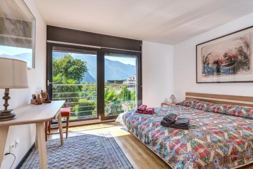 a bedroom with a bed and a desk and a window at Casa Oliver, tra la Calanca e i castelli di Bellinzona in Grono