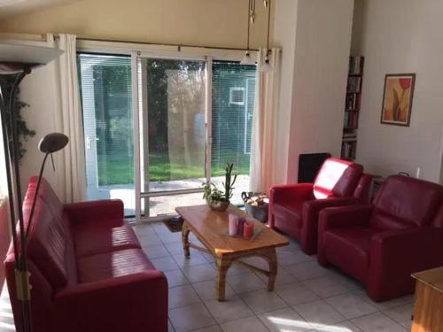 a living room with two red chairs and a coffee table at Bungalow 052 in Petten