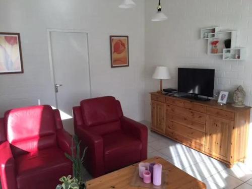 a living room with two red chairs and a television at Bungalow 052 in Petten