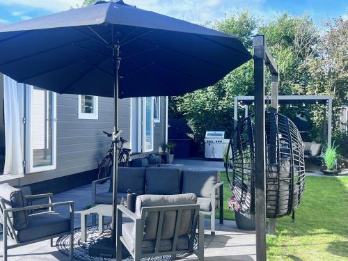 a large blue umbrella on a patio with two chairs and a table at Chalet 5 in Petten