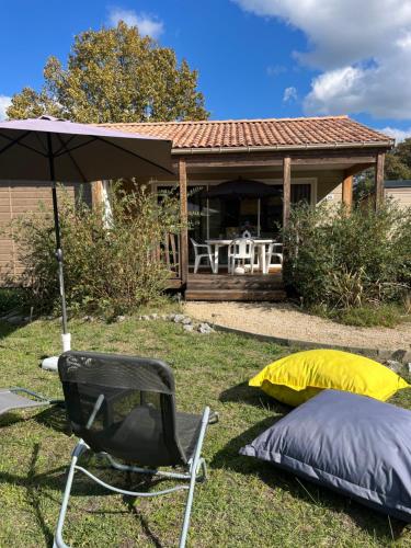 a chair and an umbrella and a tent in the yard at CHALET 10 chaleureux tout confort dans domaine avec Piscine au cœur des Landes bord de Lac avec plage aménagée in Labouheyre