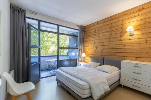 Un dormitorio con una cama con una pared de madera. en SAINT LARY Appartement Royal Milan 8 personnes, en Saint-Lary-Soulan