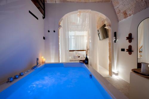 a large blue swimming pool in a room with a window at Archè Luxury private Spa in Polignano a Mare
