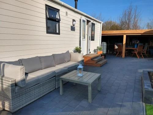 eine Couch auf einer Terrasse mit einem Tisch in der Unterkunft J 019 in Petten