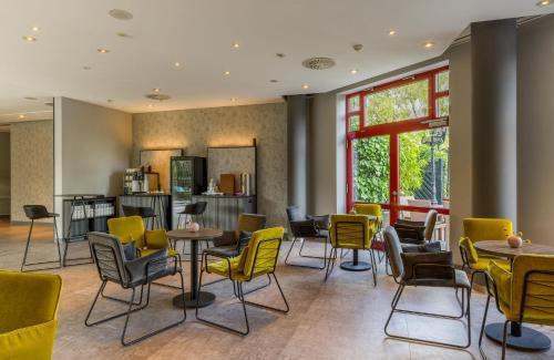 a restaurant with yellow chairs and tables at elaya hotel frankfurt oberursel in Oberursel