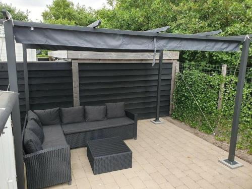 eine Terrasse mit einer Couch unter einem Sonnensegel in der Unterkunft J 020 in Petten