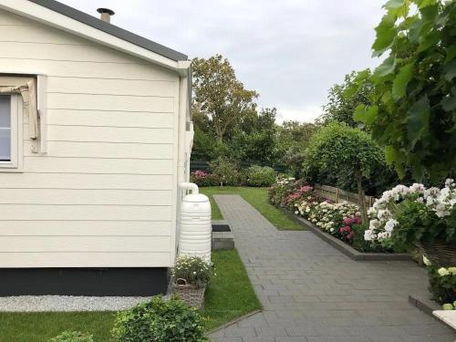 ein weißes Haus mit einem Garten mit Blumen in der Unterkunft J 059 in Petten
