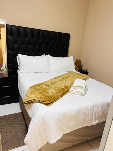 a large bed with a gold blanket on it at Palm Rest in Pretoria