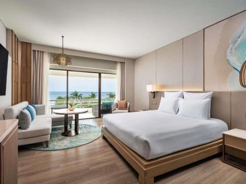 a bedroom with a bed and a living room at Pullman Phuket Karon Beach Resort in Karon Beach