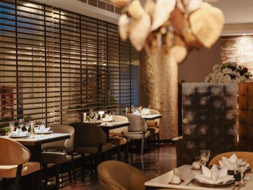 un restaurant avec des tables et des chaises et une grande fenêtre dans l'établissement Pullman Phuket Karon Beach Resort, à Karon Beach