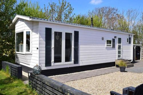 eine kleine weiße Hütte mit schwarzen Fensterläden in der Unterkunft J 062 in Petten
