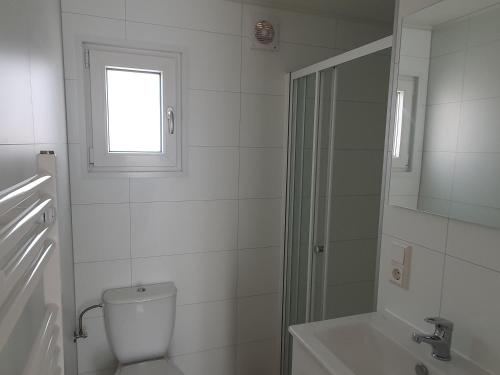 ein weißes Badezimmer mit Toilette und Dusche in der Unterkunft Chalet 87 in Petten