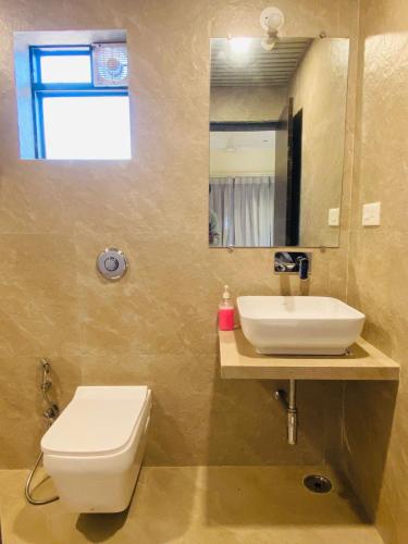 a bathroom with a toilet and a sink and a mirror at SHARDUL HERITAGE THE RESORT in Mahabaleshwar