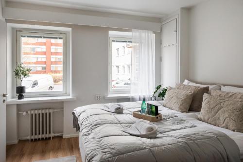 ein weißes Schlafzimmer mit einem Bett und zwei Fenstern in der Unterkunft Snowlight Apartment By BookLapland in Rovaniemi