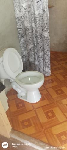 a white toilet in a bathroom with a wooden floor at CAMUNGO jungle Lodge in indigenous community ALL INCLUSIVE in Puerto Franco