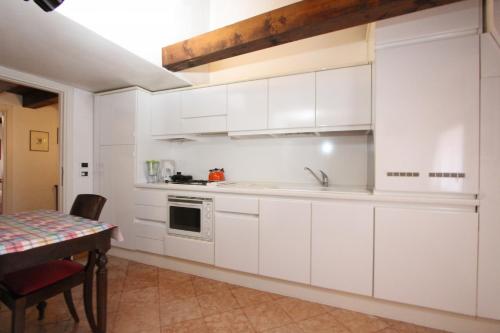 eine weiße Küche mit einem Waschbecken und einem Tisch in der Unterkunft Zoia Terrace view on St Marks Basilica 150mt in Venedig