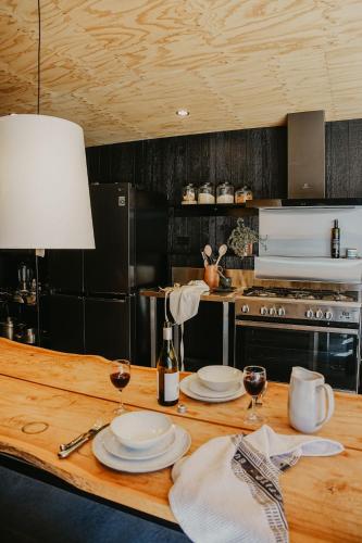a kitchen with a wooden table with plates and wine glasses at Esperance Chalet Village in Esperance