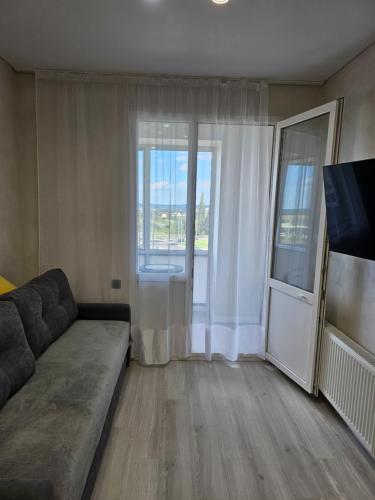 un salon avec un canapé et une grande fenêtre dans l'établissement Квартира в Рівному біля луцького кільця, à Rivne
