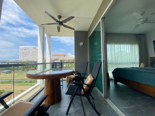een slaapkamer met een balkon met een bed en een tafel en stoelen bij The gallery condominium Ben in Jomtien Beach