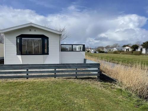 ein weißes Haus mit schwarzen Fenstern auf einem Feld in der Unterkunft J 134 in Petten