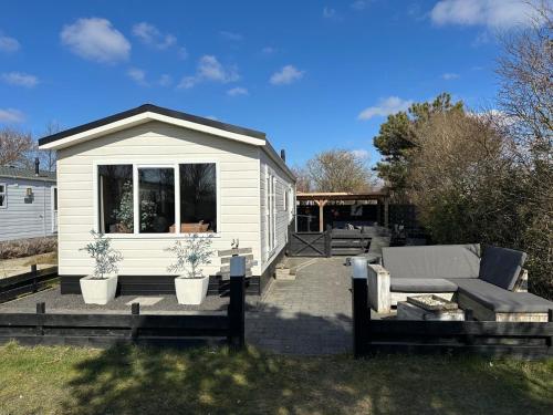 a small white shed with a couch and a patio at Chalet 218 in Petten