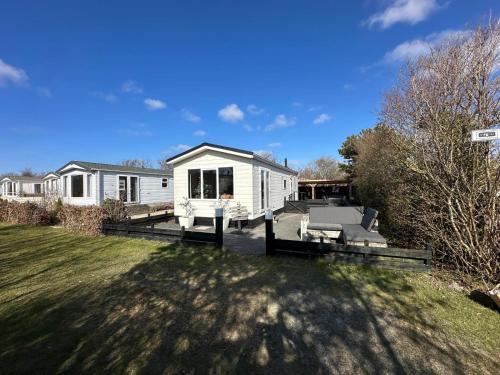 a white house with a patio and a yard at Chalet 218 in Petten